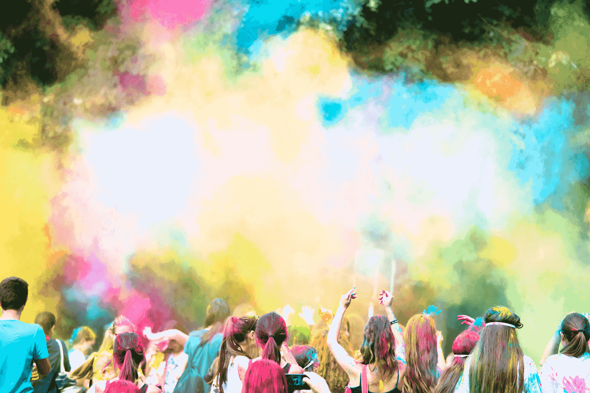 A group of multicultural people throw coloured powder in the air as they celebrate the Indian festival of Holi. 